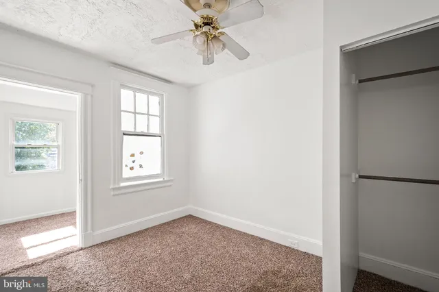 an empty room with windows and fan