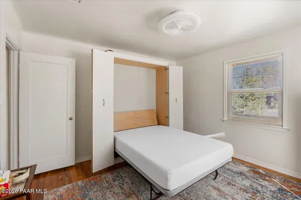 a bedroom with a white bed and wooden floor