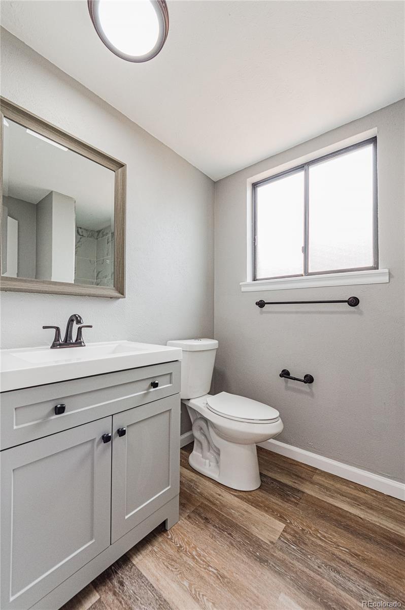 10091 Yates Street Westminster, CO 80031 - Photo 18 of 40 a bathroom with a toilet a sink a vanity and mirror