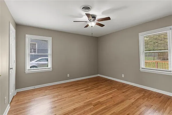 a view of empty room with wooden floor and fan