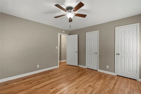 an empty room with wooden floor and ceiling fan