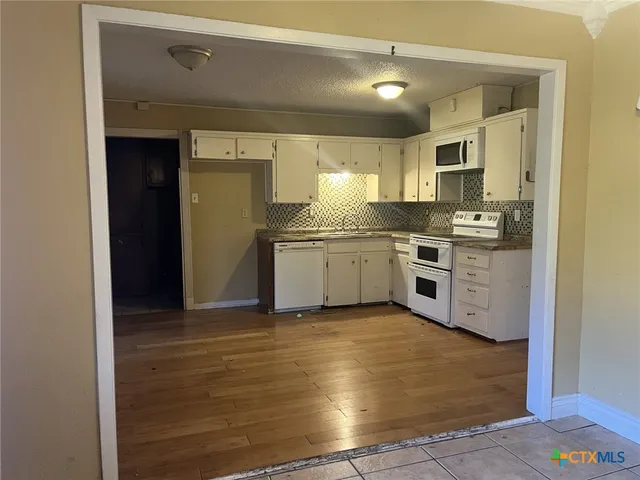 a kitchen with stainless steel appliances granite countertop a stove a sink and white cabinets