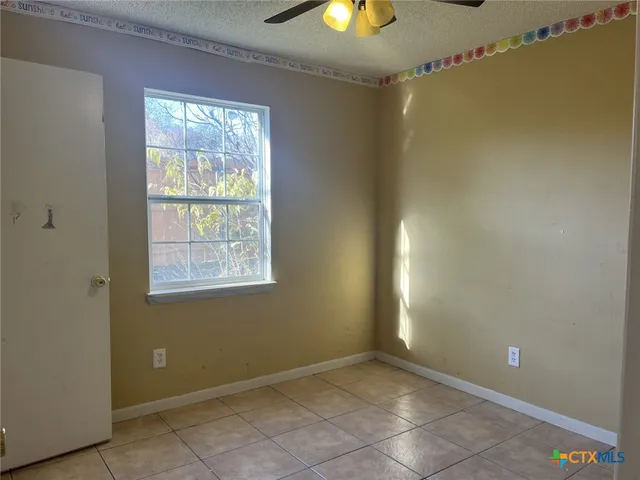 an empty room with a window and chandelier fan