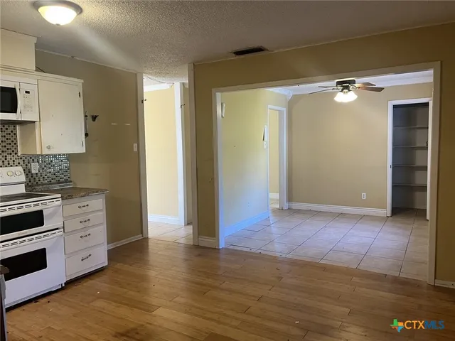 a view of an empty room with cabinet and wooden floor