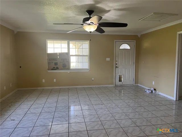 an empty room with windows and ceiling fan