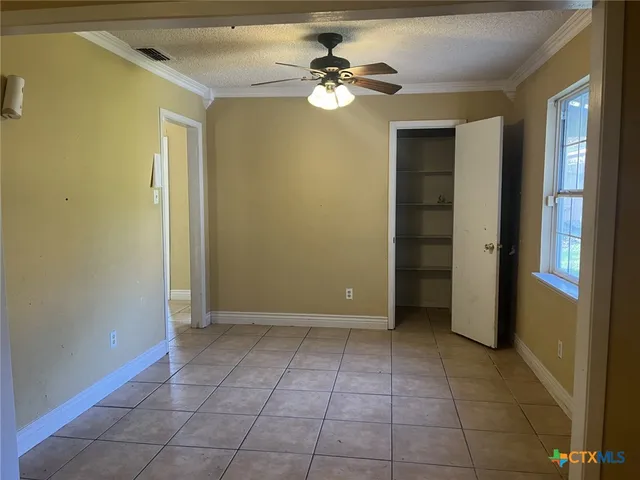 a view of an empty room with closet and a ceiling fan