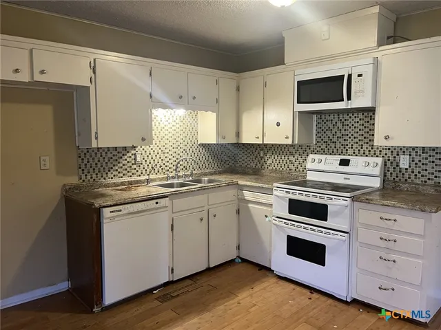 a kitchen with granite countertop white cabinets and white appliances