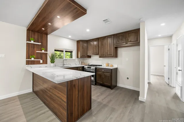 a kitchen with stainless steel appliances granite countertop a stove top oven a sink dishwasher and a refrigerator with wooden floor