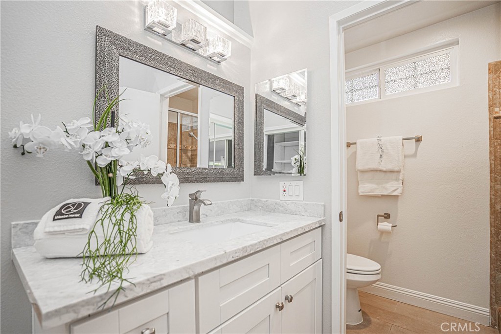 1301 Eltham Place Fullerton, CA 92833 - Photo 16 of 26 a bathroom with a granite countertop sink a toilet and a mirror