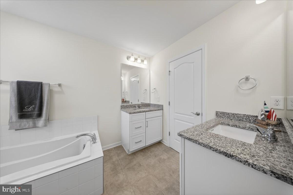 38023 Cross Gate Road Millville, DE 19967 - Photo 17 of 37 a bathroom with a granite countertop sink and a bathtub