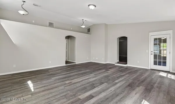 a view of an empty room with wooden floor and a window