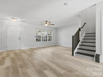 a view of an empty room with wooden floor and fan