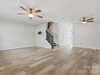a view of an empty room with wooden floor and a ceiling fan