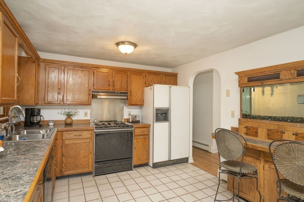 54 Gorham Street Rehoboth, MA 02769 - Photo 7 of 40 a kitchen with stainless steel appliances granite countertop a stove a refrigerator a sink dishwasher a dining table and chairs with wooden floor