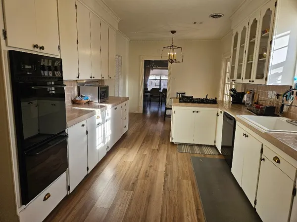 a kitchen with a sink wooden floor and stainless steel appliances