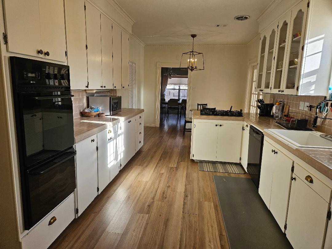 710 North Avenue C Elgin, TX 78621 - Photo 7 of 32 Kitchen featuring backsplash, hanging light fixtures, ornamental molding, white cabinets, and dark wood finished floors