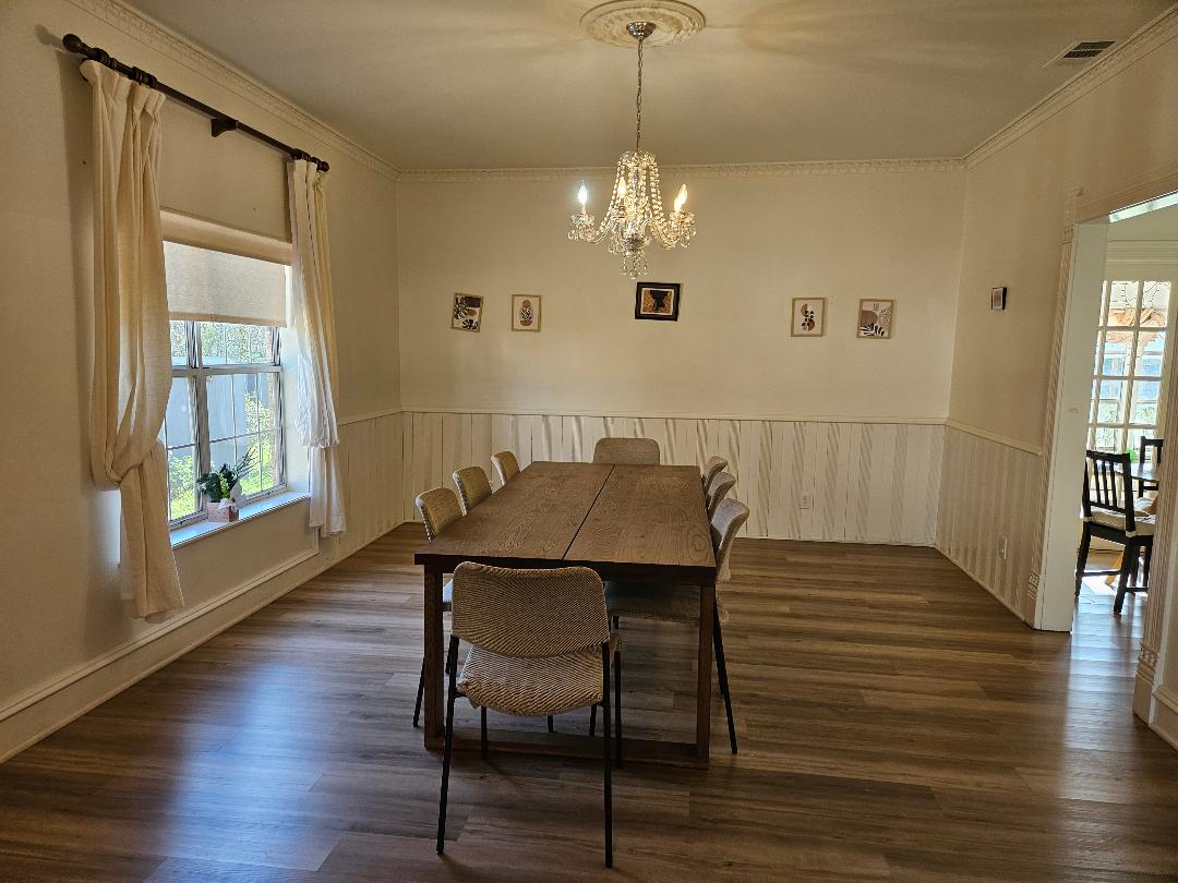 710 North Avenue C Elgin, TX 78621 - Photo 8 of 32 Dining room with vinyl plank flooring, a chandelier, wainscoting, and ornamental molding