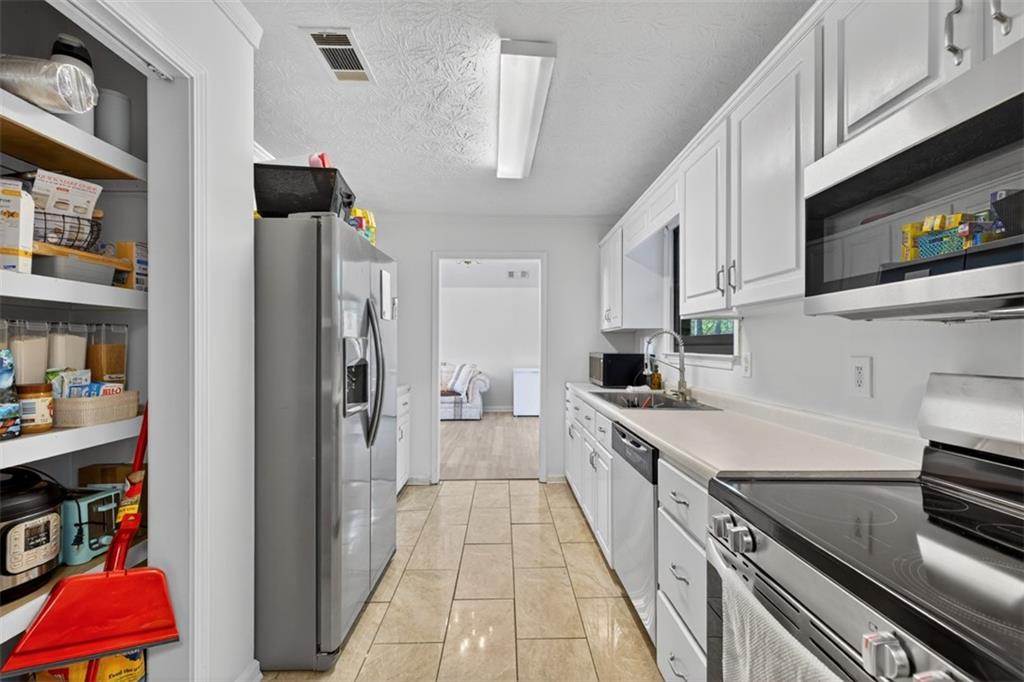 494 Spring Street Social Circle, GA 30025 - Photo 7 of 21 a large kitchen with stainless steel appliances granite countertop a refrigerator a stove and a sink