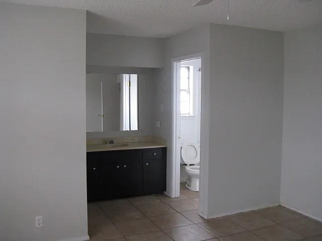 4004 Vicky Street Big Spring, TX 79720 - Photo 5 of 13 Bathroom vanity featuring a dark wood-finish cabinet with silver-tone hardware, a light-colored countertop, and an integrated sink with a chrome faucet