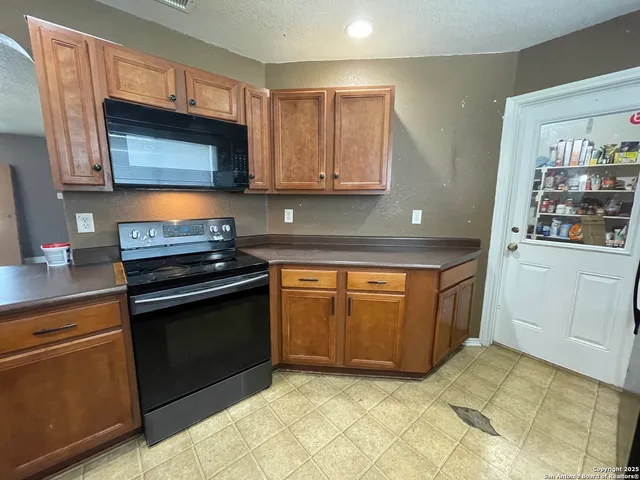 a kitchen with stainless steel appliances granite countertop a stove a sink and a microwave