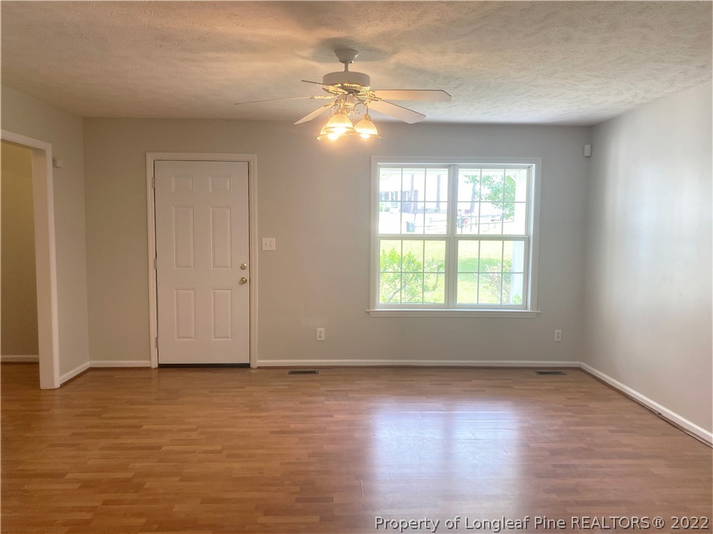 1298 Roundabout Road Cameron, NC 28326 - Photo 5 of 29 an empty room with wooden floor and windows with curtains