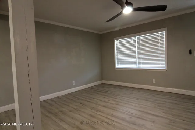 a view of an empty room with wooden floor and a window