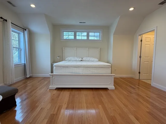 a spacious bedroom with a bed and wooden floor
