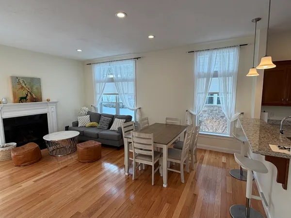 a living room with furniture a fireplace a flat screen tv and wooden floor
