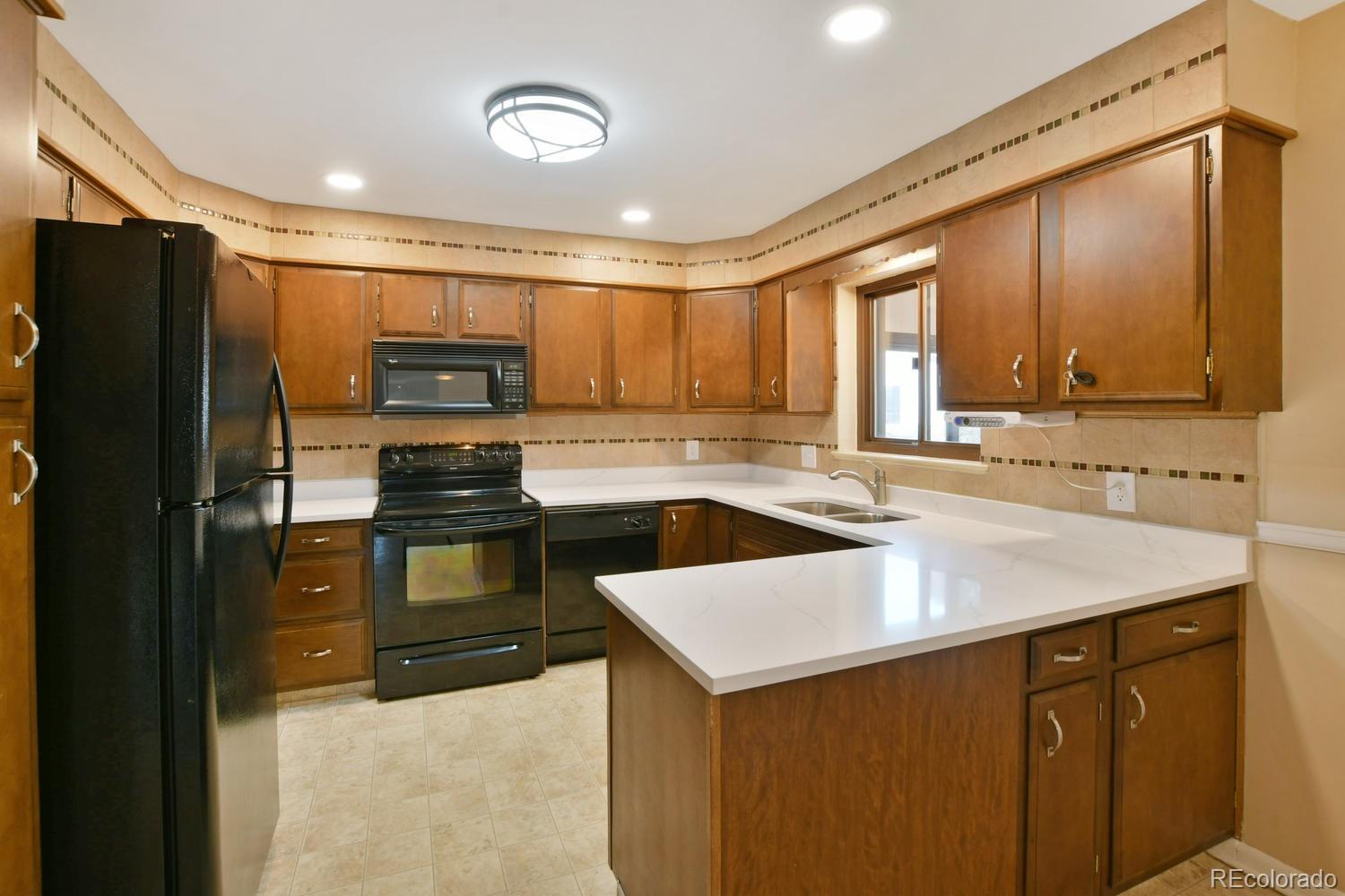4660 Quay Street Wheat Ridge, CO 80033 - Photo 10 of 37 a kitchen with a sink a stove a refrigerator and a microwave