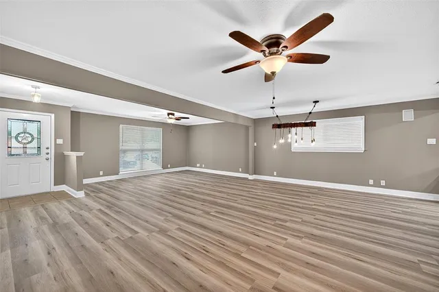 a view of an empty room with window and a ceiling fan