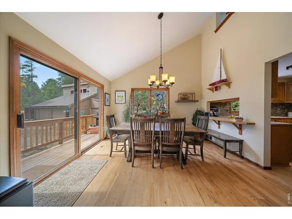 a dining room with furniture wooden floor a rug a potted plant and a chandelier