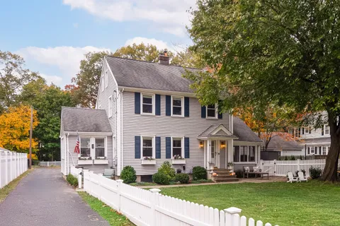 a front view of a house with a garden and trees