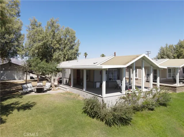 a view of a white house with a small yard and sitting area