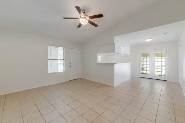 an empty room with chandelier fan and windows