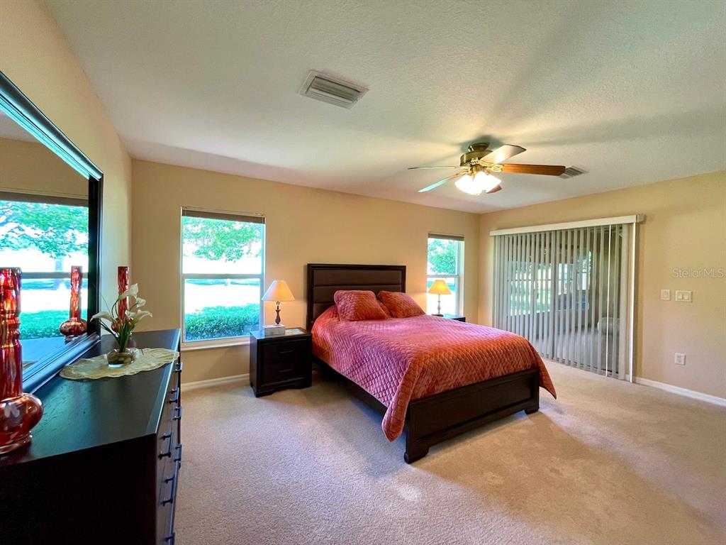 16026 Southwest 14th Avenue Road Ocala, FL 34473 - Photo 42 of 79 a spacious bedroom with a bed and a chandelier