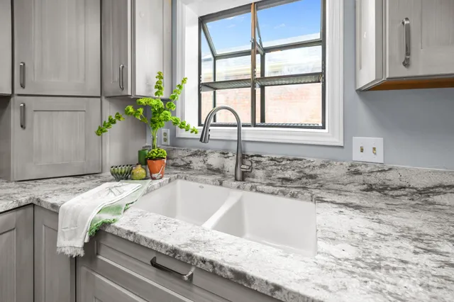 a bathroom with a granite countertop sink and a window