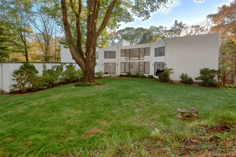 a front view of a house with a garden and trees