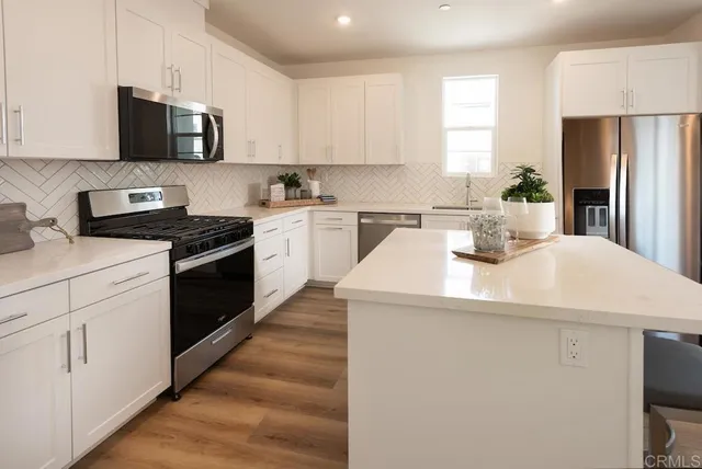a kitchen with a sink a stove top oven and white stainless steel appliances