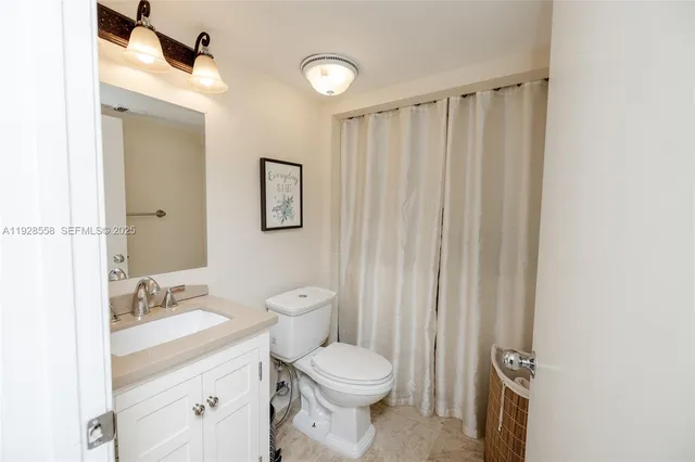 a bathroom with a sink a toilet a mirror and shower curtain
