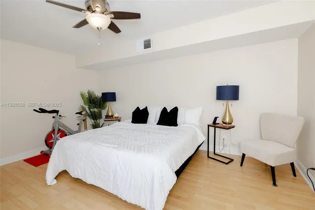 a bedroom with a bed a chair and a potted plant on the dresser