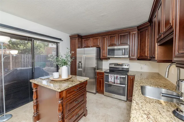 a kitchen with kitchen island granite countertop a stove top oven microwave and refrigerator