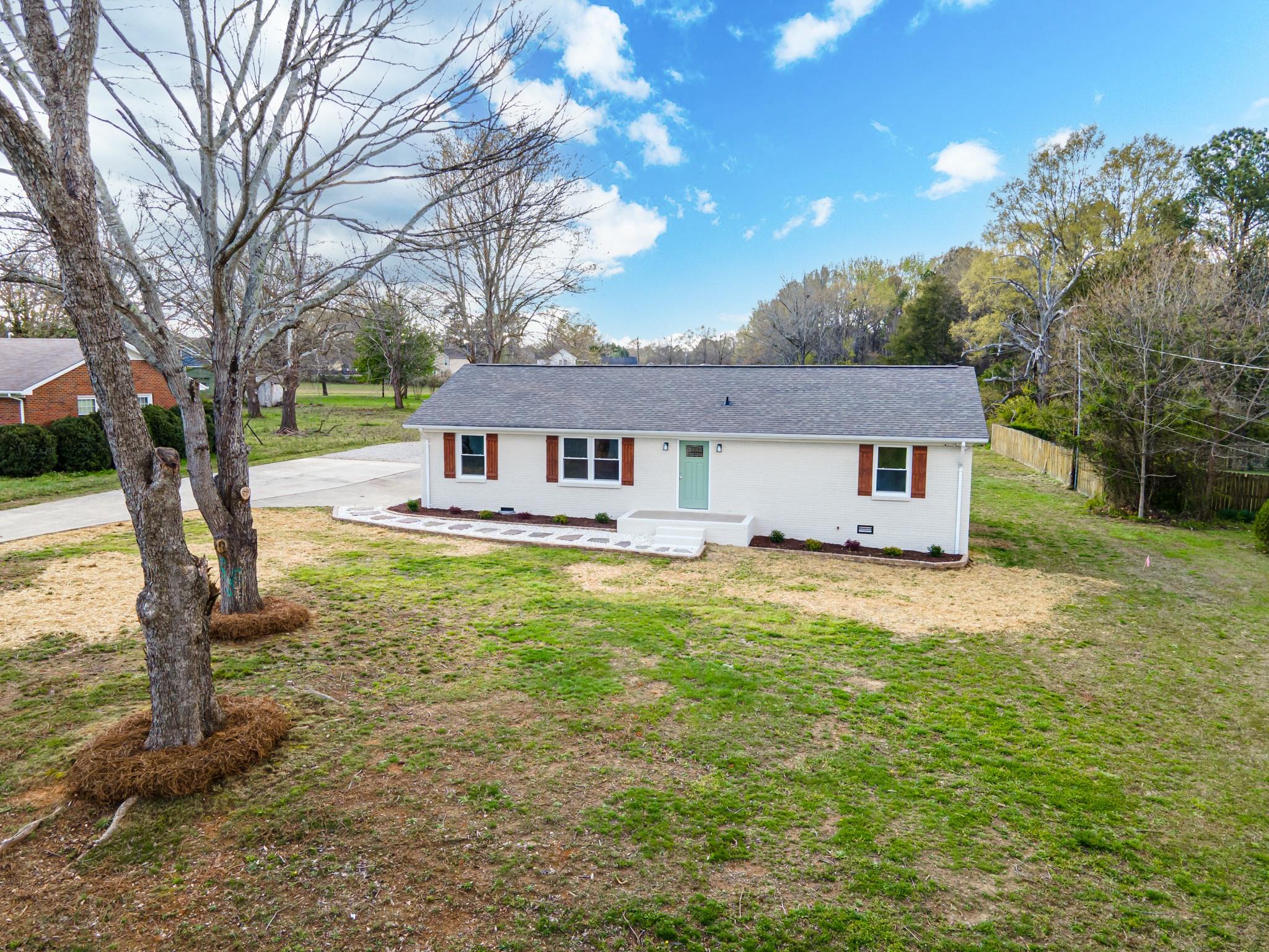 a front view of a house with a yard tree and outdoor seating