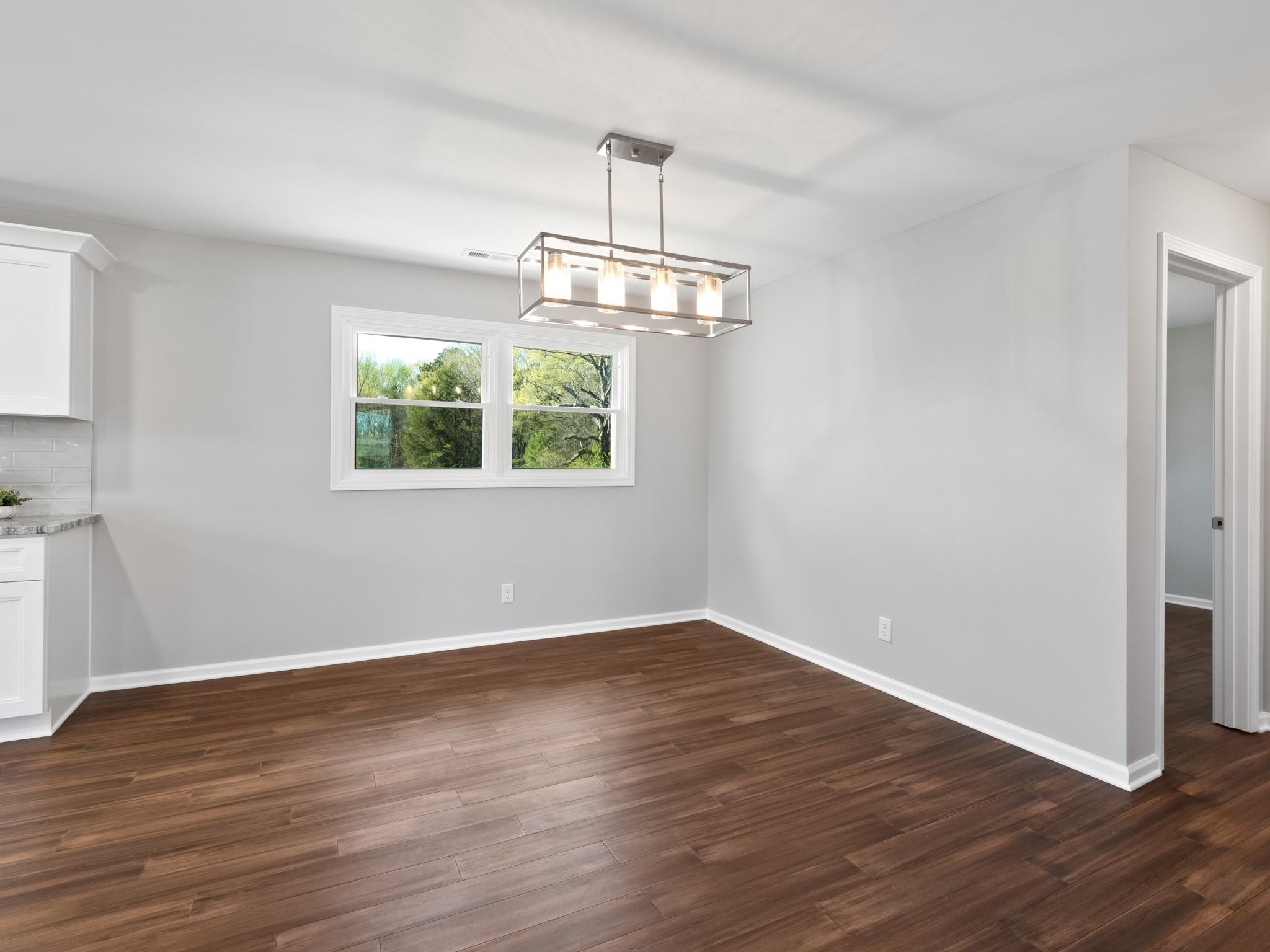 1813 Timber Ln Drive Monroe, NC 28110 - Photo 29 of 35 an empty room with wooden floor chandelier and windows