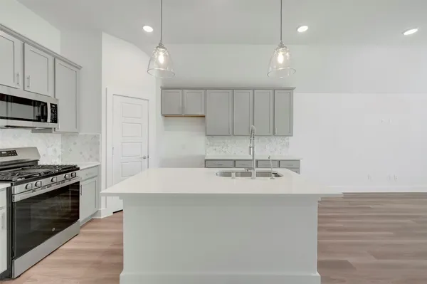 a view of kitchen with kitchen island a sink stainless steel appliances and cabinets