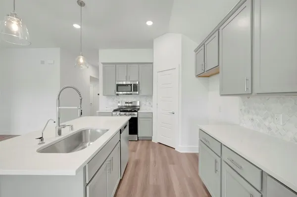 a large white kitchen with wooden floor and stainless steel appliances