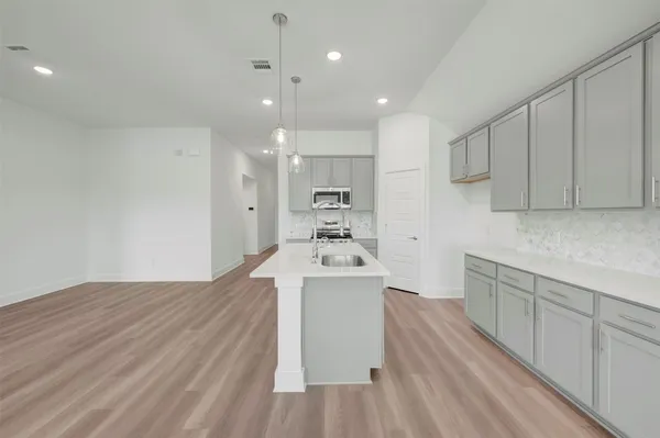 a view of a kitchen with a sink and dishwasher with wooden floor