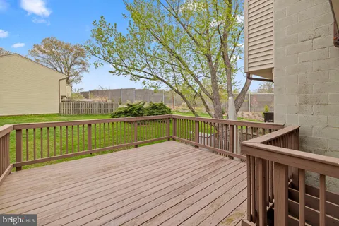 a view of deck with wooden floor and fence with a large tree