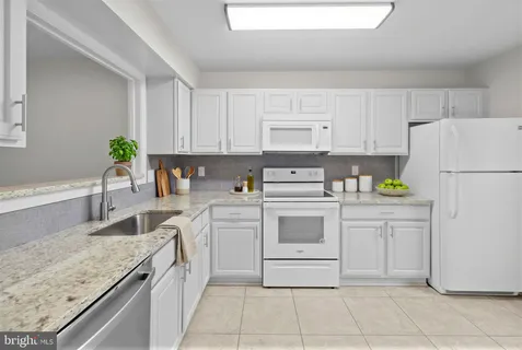 a kitchen with kitchen island granite countertop cabinets and white appliances