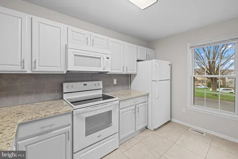 a kitchen with white cabinets and white appliances