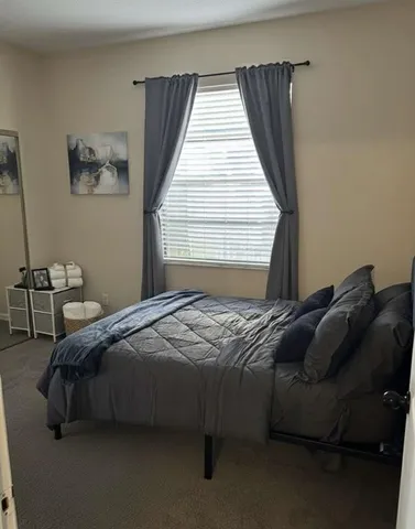 a bedroom with bed couch and window